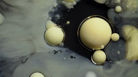Close-up golden acrylic paint bubbles spreading on deep black surface Stock Footage 128764258