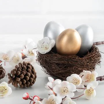 Close up of golden and silver Easter eggs in the nest with white plum flower. Stock Photos