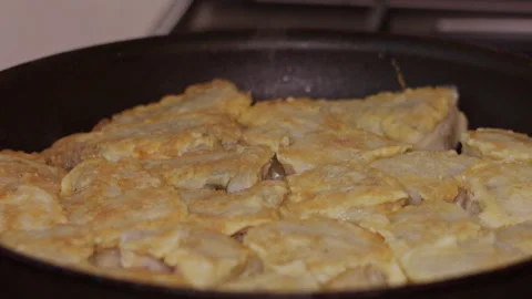 Close-up of golden battered fish pieces frying in a black skillet Stock-Footage 342384765
