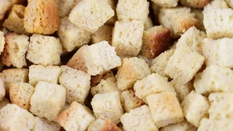 Close-up of golden bread croutons rotating. Crunchy toasted bread cubes tex.. Stock Footage 343796112