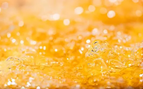 Close-up of golden liquid with bubbles and light reflection Stockfoto's