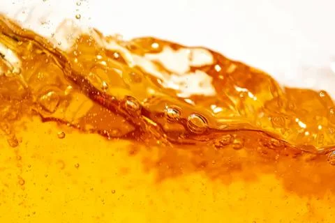 Close-up of golden liquid splash with bubbles and froth Stock Photos