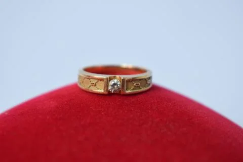 Close Up Golden ring with diamond on red carpet texture Background Stock Photos