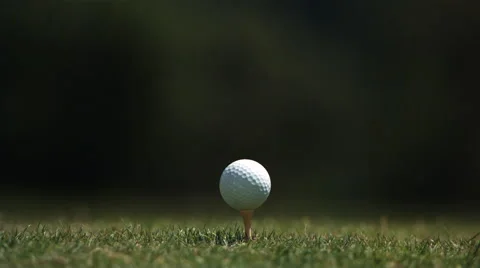 Close-up of golf ball on tee and club head striking it in ultra-slow motion Stock Footage