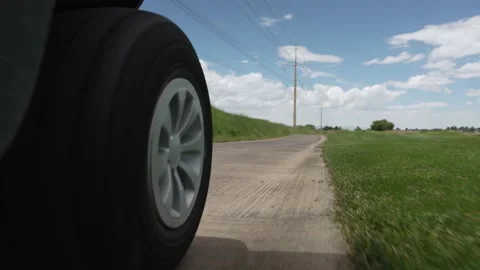Close up of golf cart wheel as it drives along path through course on sunny day Stock Footage 202045026