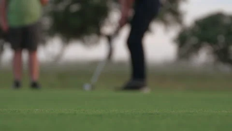 Close-up of a golf hole with a golfer putting on the green to make a hole. Stock Footage 167860321