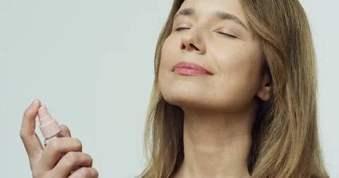 Close up of the good looking smiled Caucasian woman spraying parfume on her neck Video stock 111519619