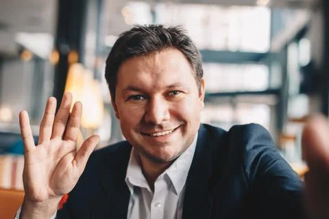 Close-up of good looking young man making a video call in a cafe bar during a Stock Photos