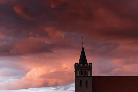 Close up gothic church tower with dramatic sunset red clouds Stock Photos