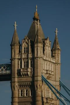 Close up of a gothic stone tower of Tower Bridge with blue suspension chains Фото