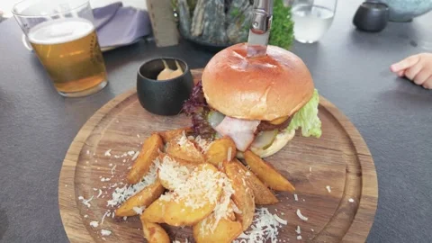Close-up of Gourmet Burger and Potato Wedges Served with Beer at Outdoor Stock Footage 345686953