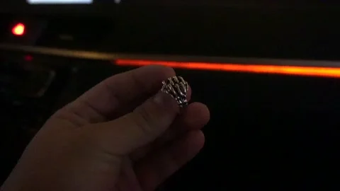 Close-up grabbing a ring shaped like crossed bone fingers at night in 4K Stockbeeldmateriaal 155869592