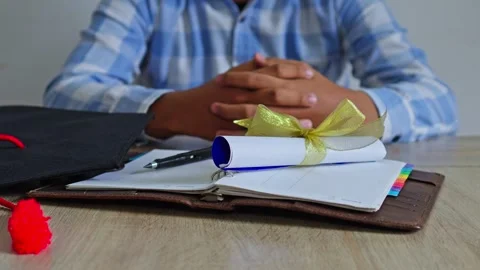 Close-up of graduation scroll being set on wooden table with leather notebook Stock Footage 333940029
