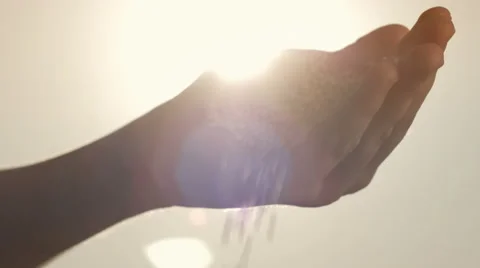 Close-up of grains falling out of a hand against the sky and sun Stock Footage 67040985