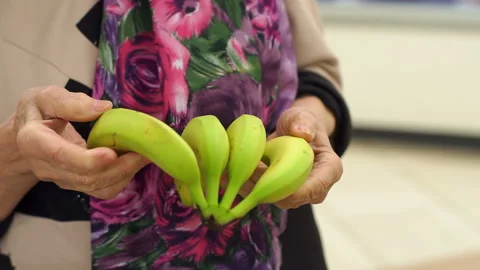 Close-up grandmother of eighty years buys fresh bananas in the supermarket. Stock Footage 109327481
