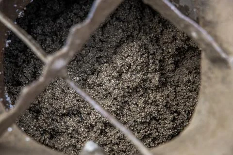 Close Up of Granular Metallic Particles in a Container with Metal Grate Foto stock