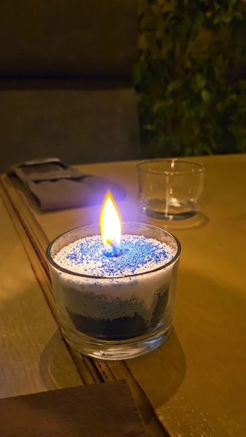 Close-up of granular wax candle burning with ultraviolet halo flame on table Stock Footage 346239200
