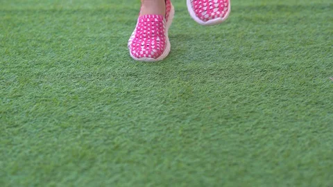 Close up grass and shoes of kid jogging and jump on grass field Stock-Footage 129580409