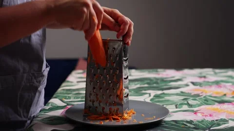 Close up of grating fresh carrot with kitchen grater during homemade cooking Stock-Footage 343544123
