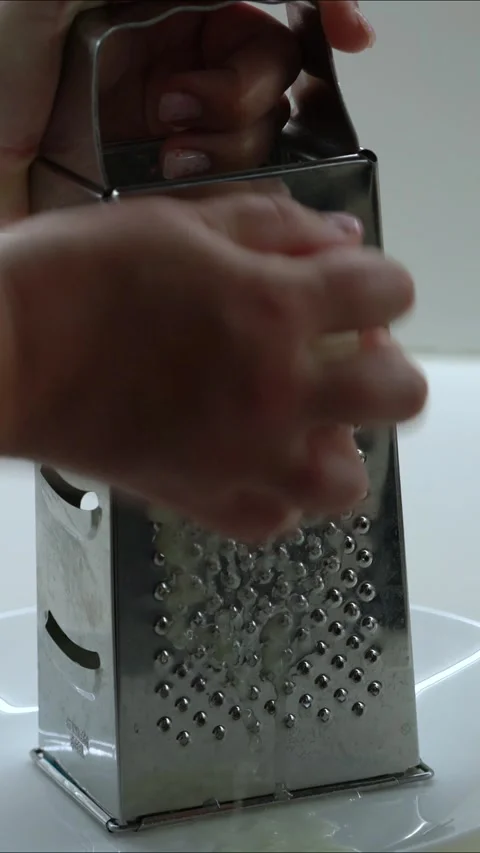 Close up of grating onion on metal kitchen grater 스톡 동영상 330052242