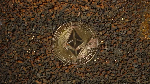 Close-Up of Gravel Exploding Outward, Revealing a Gold Ethereum Coin Beneath, Stock Footage 296388037