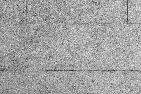 Close-up of a gray granite stone wall showing horizontal concrete tiles Stock Photos