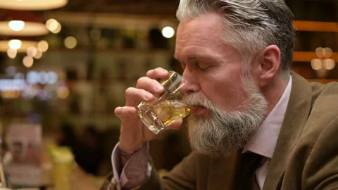 Close-up of a gray-haired bearded man enjoying whiskey alone in a bar Stock Footage 164654011