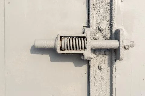 Close up a gray painted spring bolt with metal bolts and plate joins. Stock Photos