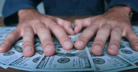 Close-up of greedy man's hands grabbing a bunch of dollars lying on the table Stock Footage 231021207