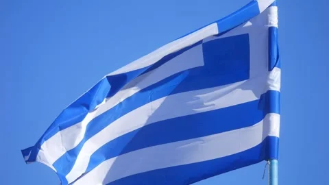 A close-up of a Greek flag waving in the wind against a clear blue sky in 4.. Stock Footage 291083376