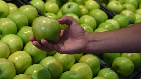 Close-up green apple in a mans hand against of a counter in market Stock Footage 244360427