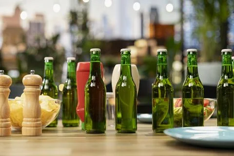 Close up of green beer bottles, chips and plates arranged on rooftop table Stock Photos