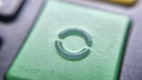 A close-up of a green button featuring a circular refresh symbol, suggesting the Stock Photos