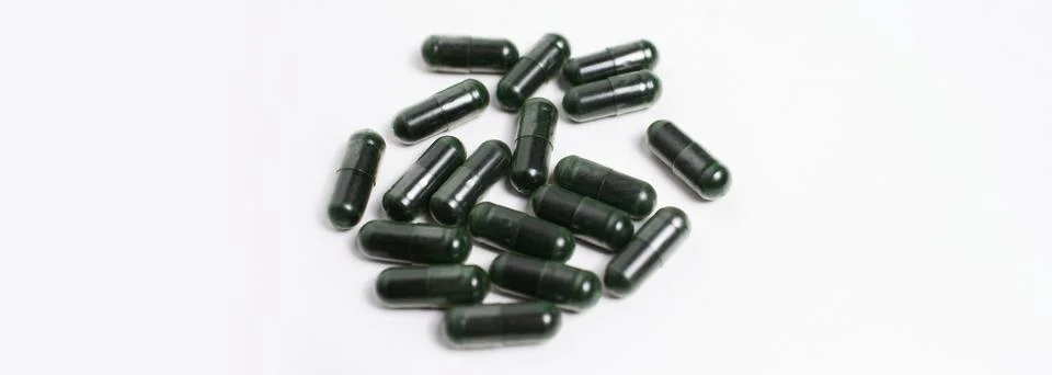 Close-up of green capsule pills isolated on white background. Panoramic banner. Stock Photos