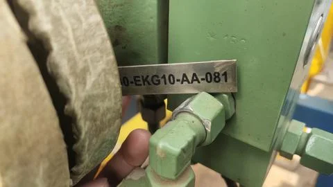A close-up of a green industrial machine component with a metal identificat.. Stock Photos