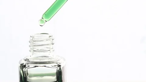 Close-up of green oil drops falling from the pipette, on white background Stock Footage 118932422