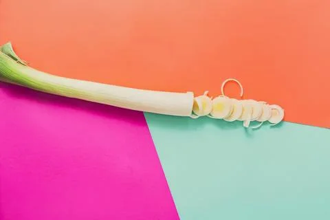 Close-up of a green onion with sprouting roots on colorful background Stock Photos
