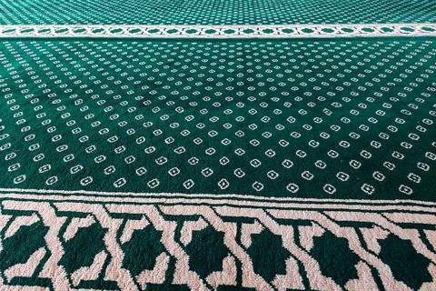 Close-up of green patterned carpet with white geometric and floral motifs. Stock Photos