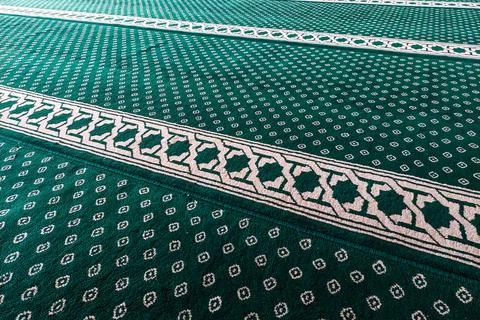 Close-up of green patterned carpet with white geometric and floral motifs. Stock Photos