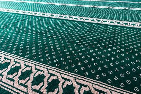 Close-up of green patterned carpet with white geometric and floral motifs. Stock Photos