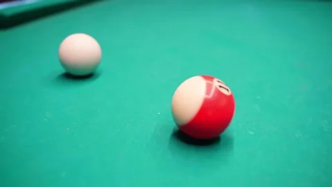 Close-up on a green pool table showing the white cue ball and a red striped Stockbeeldmateriaal 328392437