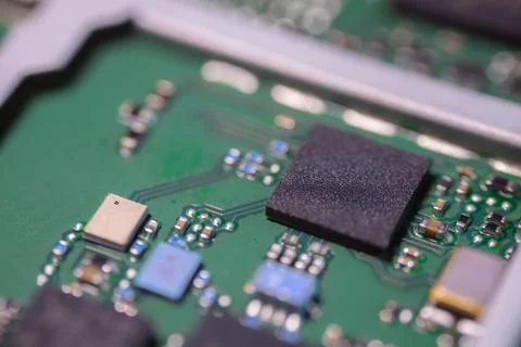 Close up of green printed circuit board with black processor chip, metallic.. Stock Photos