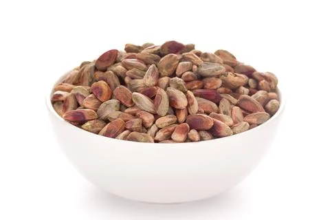 Close-up of green red pistachio kernel  (dry ) in a white ceramic bowl over w 스톡 사진