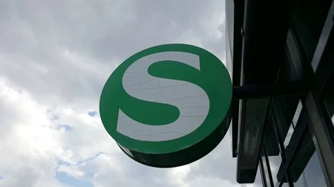 Close up of a green S-bahn sign with white letter “S”, cloudy sky in background Vídeos de archivo 81853897