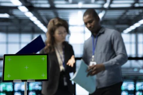 Close up of green screen tablet in front of employees overseeing server room Stock Photos