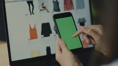 Close-up of green screen of telephone with clothes website on computer at Stock Footage 117138853