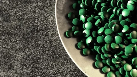Close-up of green spirulina tablets in a plate Stock Footage 317634654