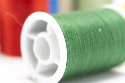Close-up of Green Thread Spool with Red and Blue Spools in Background on Wh.. Stock Photos