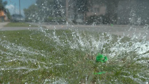 CLOSE UP: Green water balloon explodes after falling on the patch of grass. Stock Footage 96023308