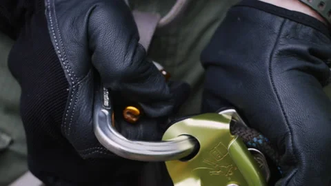 A close up of a GriGri mount with a spring hook. Man adjusts rope while belaying Stock Footage 204866135
